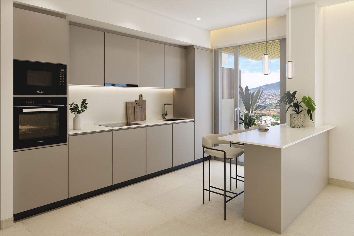Strakke keuken met inbouwapparatuur en wit aanrecht, met uitzicht op berglandschap in een appartement in Mijas