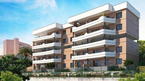 Buitenzicht op een modern 2-slaapkamer appartementengebouw in Fuengirola, Costa del Sol, omgeven door groen.