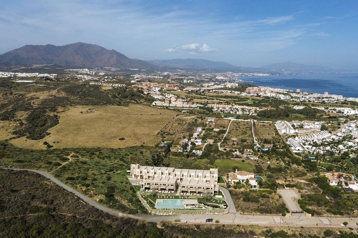 Luchtfoto van de 3-slaapkamer townhouses in Manilva, met een focus op de rustige omgeving en bergen.