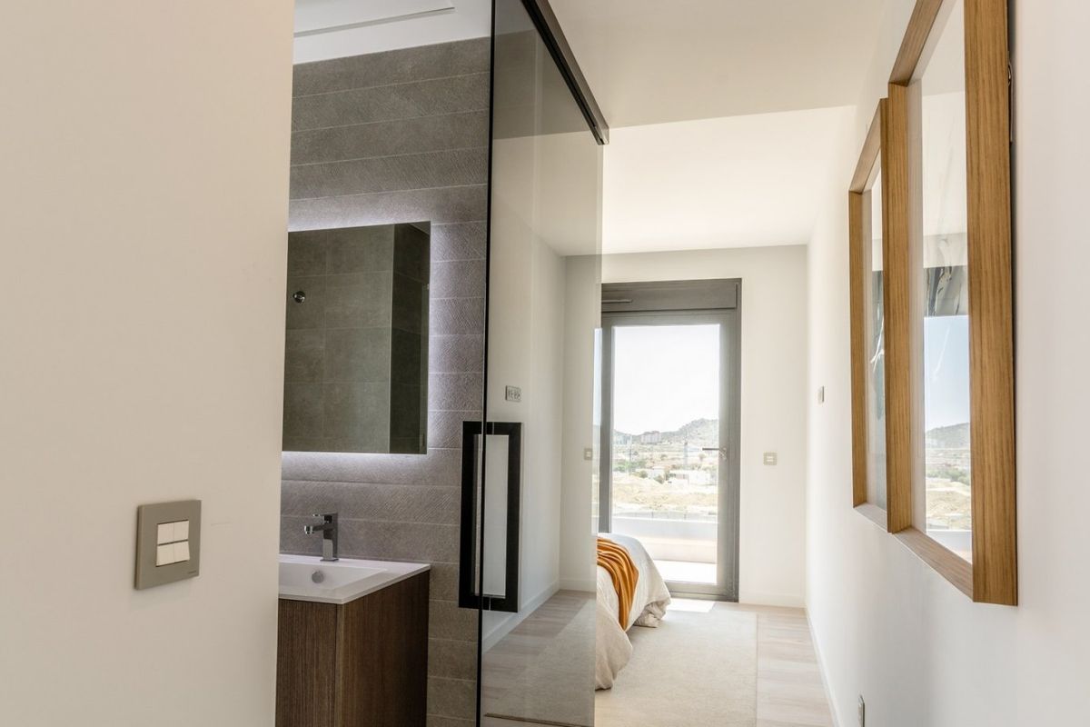 View through a glass door from the bathroom to a modern bedroom with stunning mountain views in Finestrat, Costa Blanca.