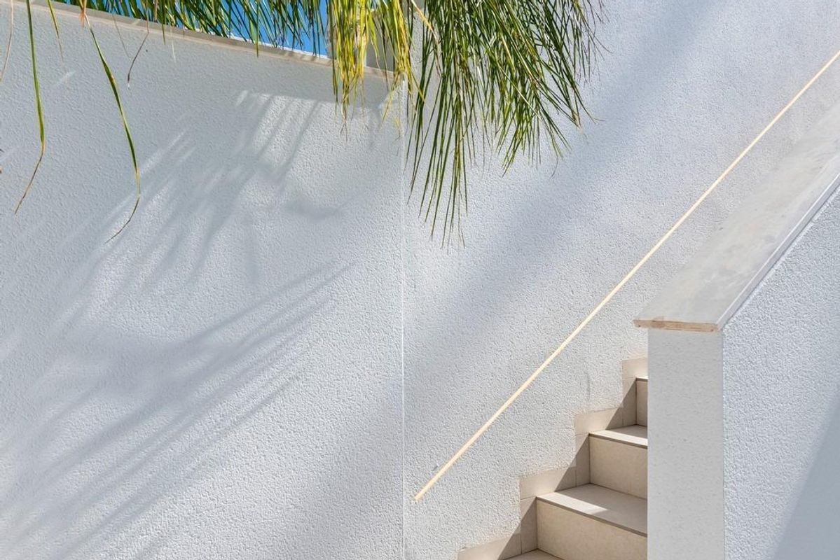 Trappen die naar het dakterras van een bungalow in Pilar de La Horadada leiden, met groene palmbomen in de buurt.