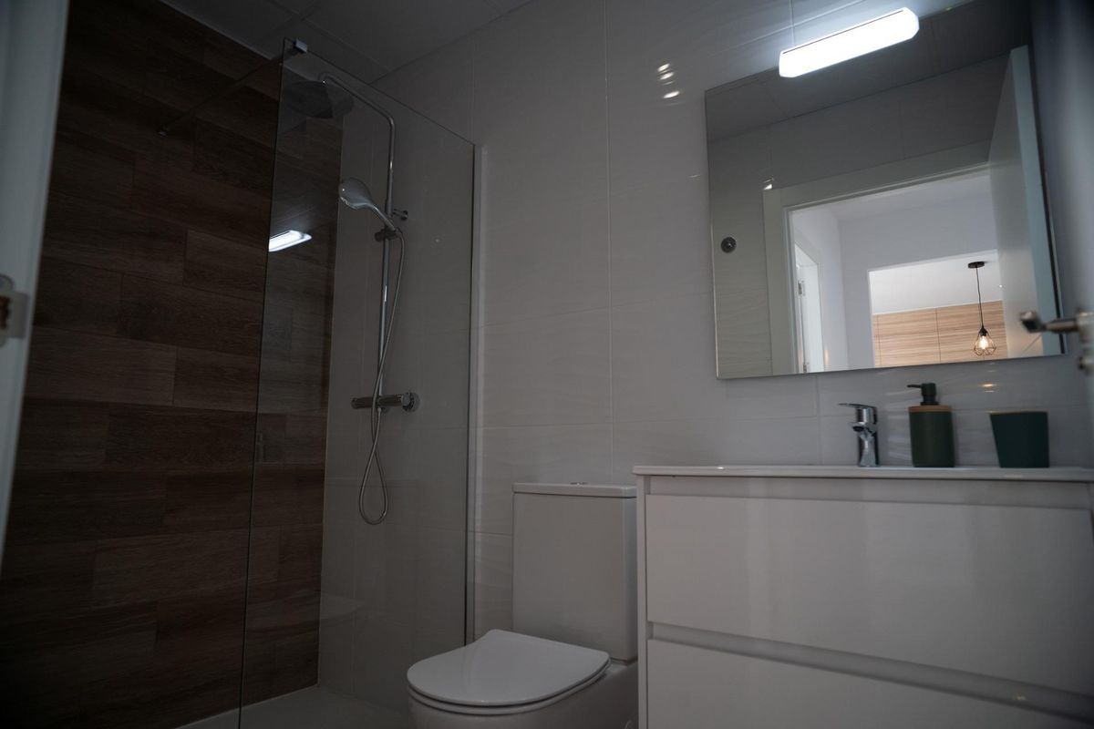 Bathroom interior with shower, toilet, and sink in a modern San Javier townhouse. Neutral tones and sleek design.
