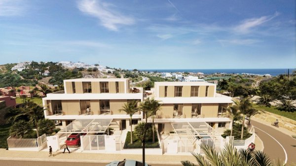 Vooraanzicht van een 4-slaapkamer townhouse in Estepona met moderne architectuur en kustomgeving.
