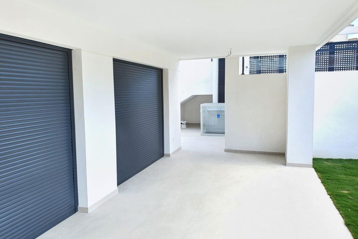 Schaduwrijke ruimte onder de villa in Manilva, met opslagruimte en rolluiken.