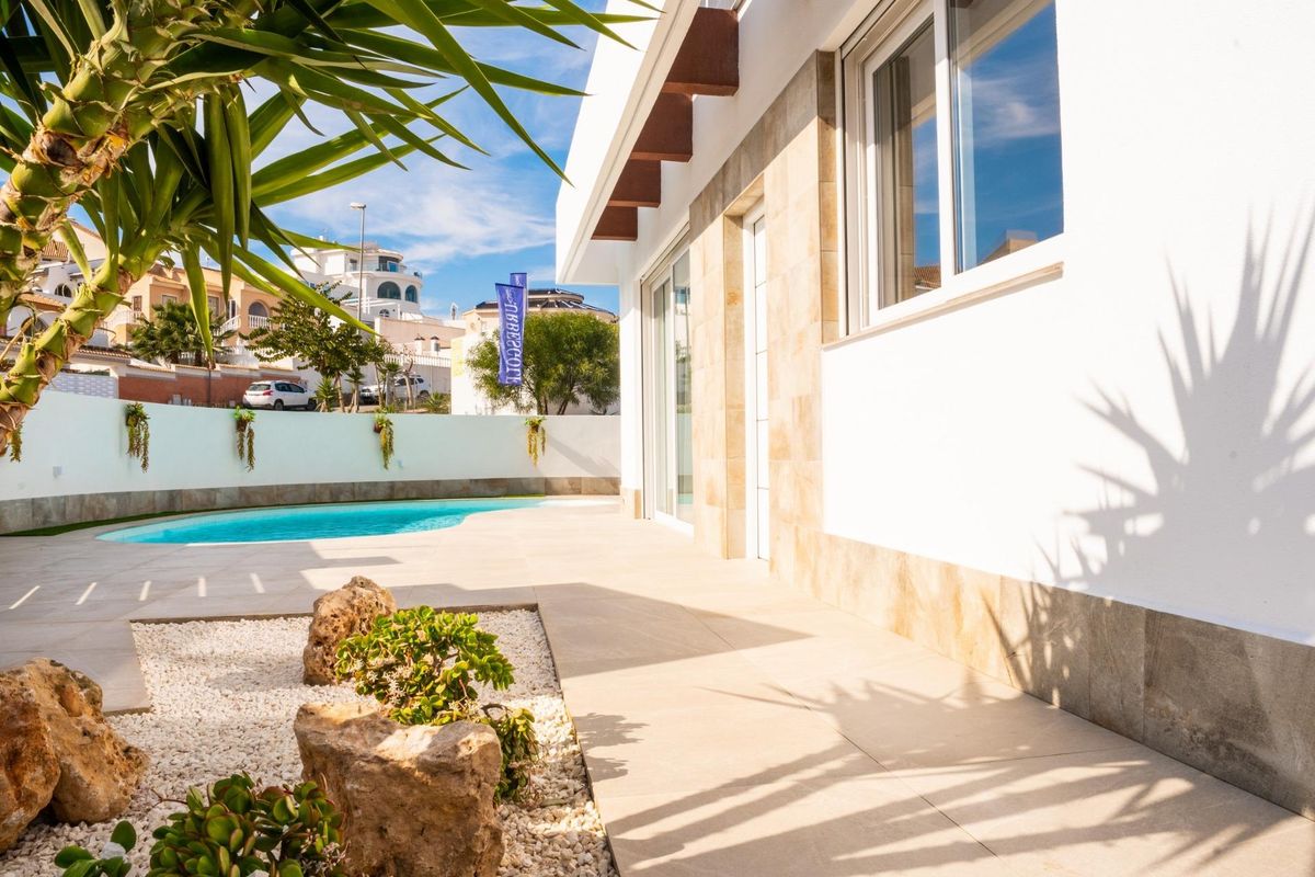 Uitzicht op de aangelegde tuin en het zwembad van de zijkant van de villa in Ciudad Quesada, met nadruk op de natuur.