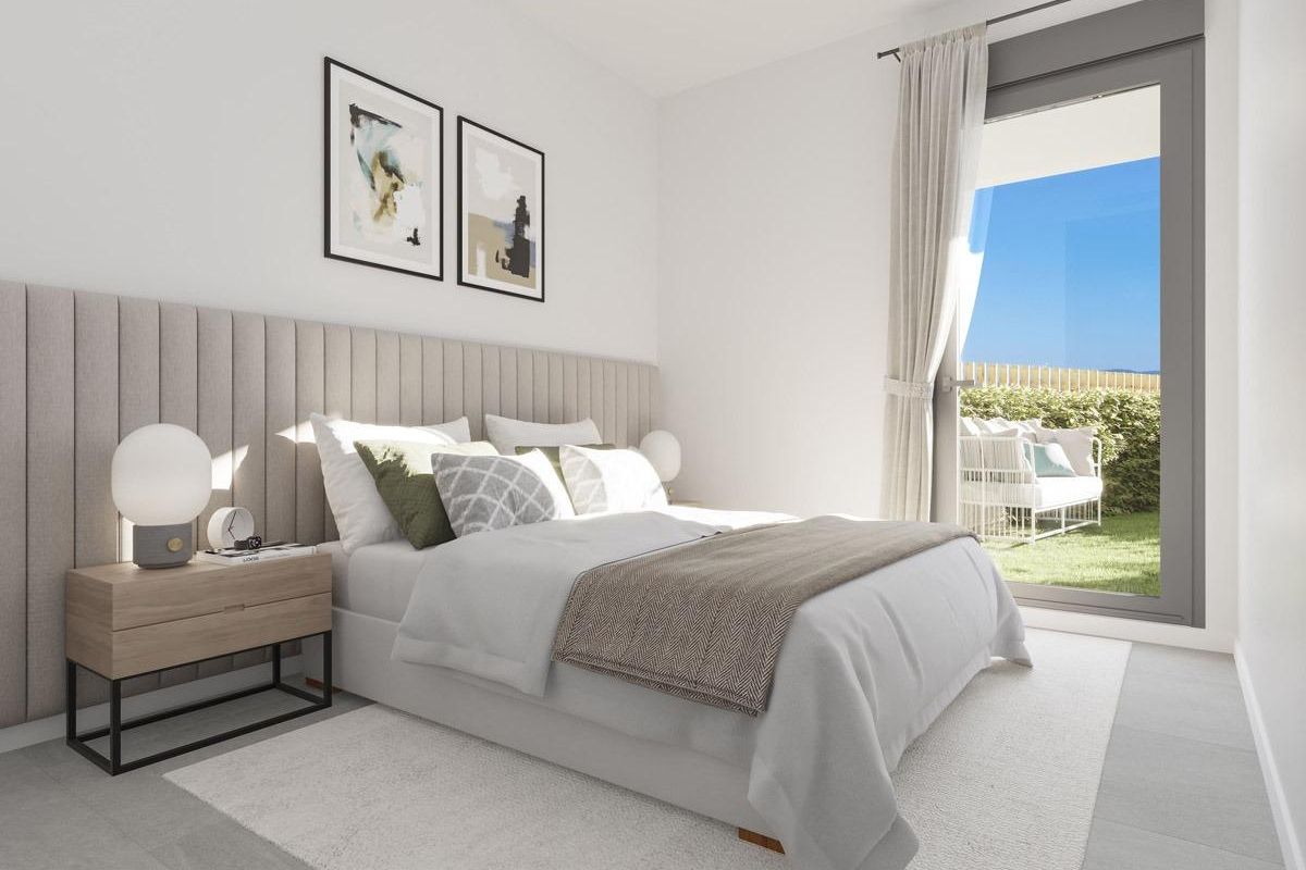 Eigentijdse slaapkamer met neutrale tinten, kunstprints en tuinzicht in Spaanse kuststad