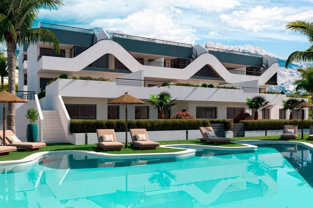 Buitenzijde van het appartementcomplex op de begane grond met een zwembad en ligbedden in Alfas del Pi.