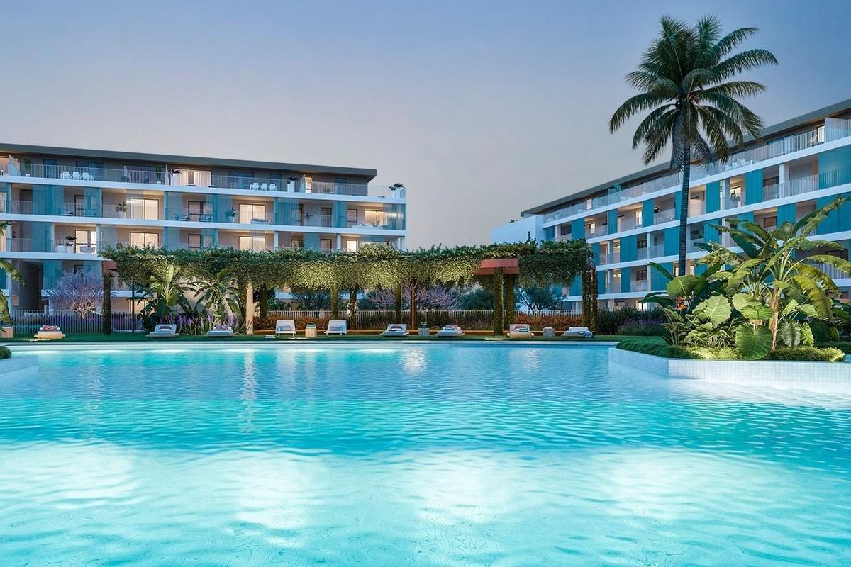 Exterior view of a modern apartment complex with large pool and palm trees in Denia, Costa Blanca North.