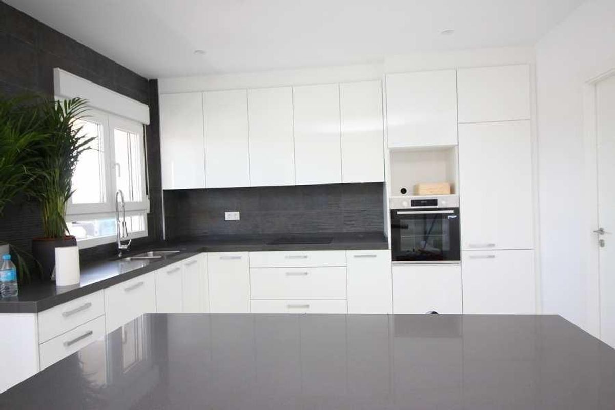 Moderne keuken in de villa in Pinoso, met strakke witte kasten en grijze aanrechtbladen.