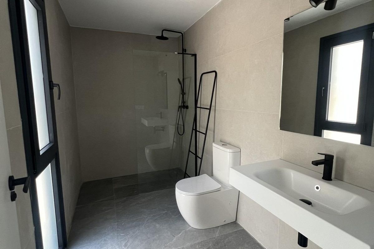 Moderne badkamer met zachte kleuren en een strakke douche in een 3-slaapkamer townhouse in Polop, Spanje.