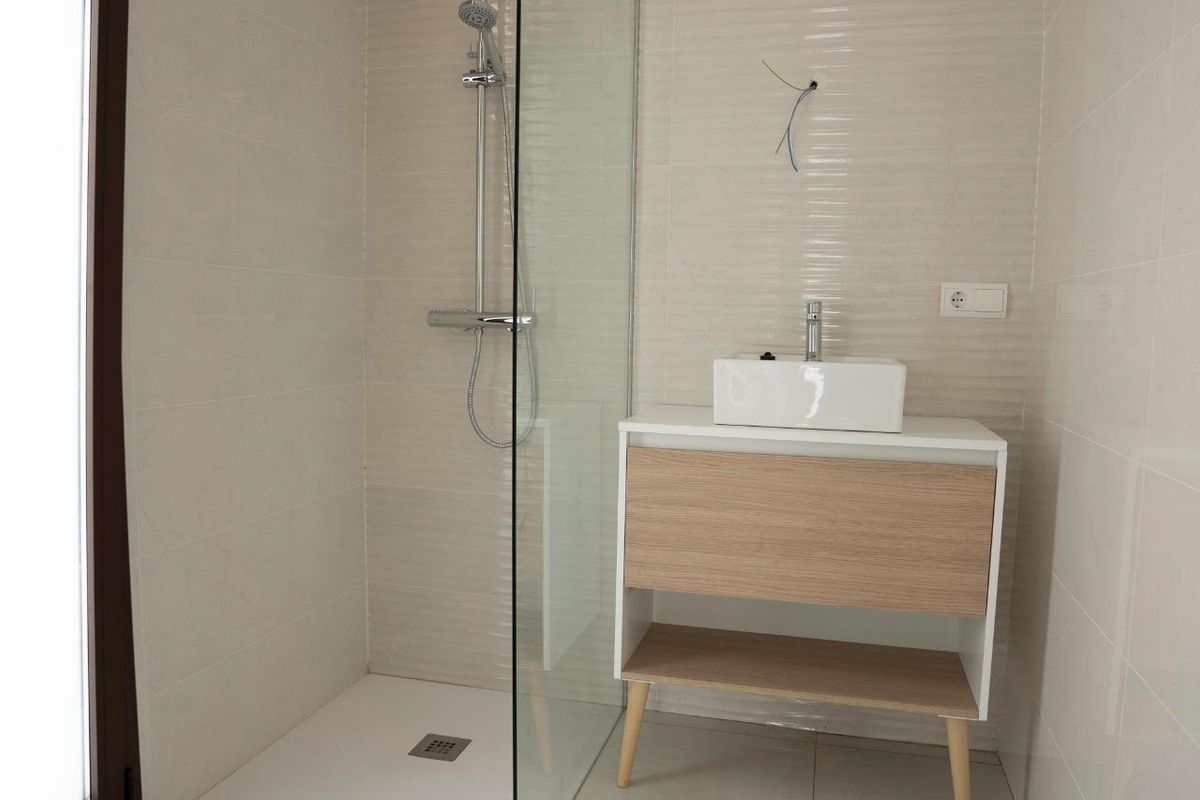 Heldere douche met glazen paneel, stijlvolle wastafel en moderne esthetiek in een villa in Polop.