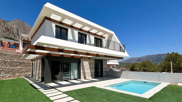 Moderne 3-slaapkamer villa in Polop met zwembad en tuin, tegen een bergachtergrond onder een heldere hemel.