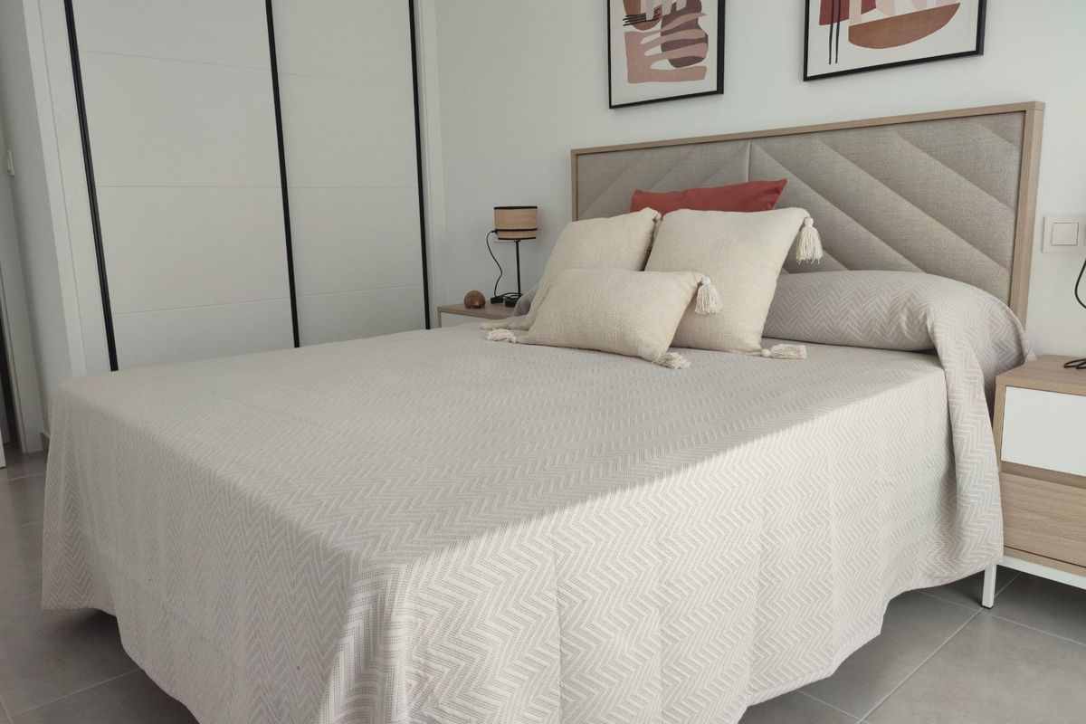 Uitnodigende hoofdslaapkamer met decoratieve kussens en zachte tinten in een 3-slaapkamer townhouse in Torre Pacheco, Spanje.