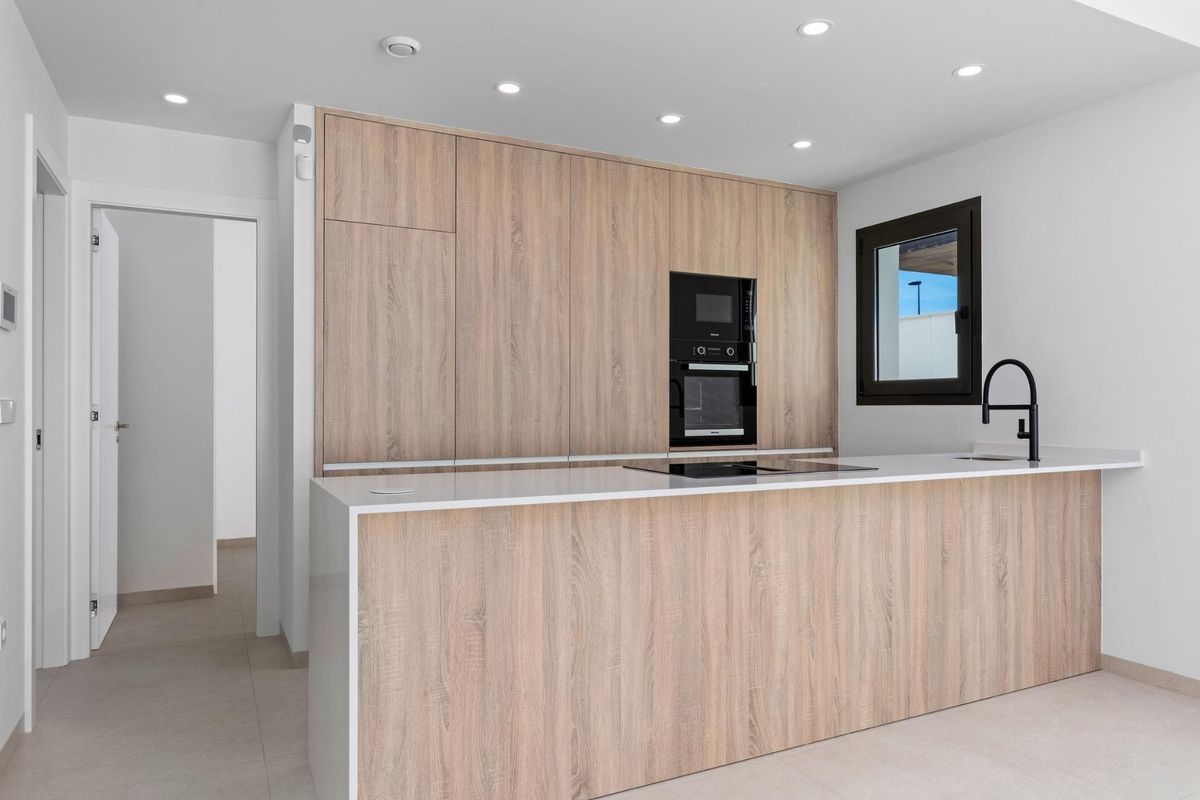 Stijlvolle keuken met lichte houten kasten in een bungalow in Pilar de La Horadada, ontworpen voor comfort en functionaliteit.