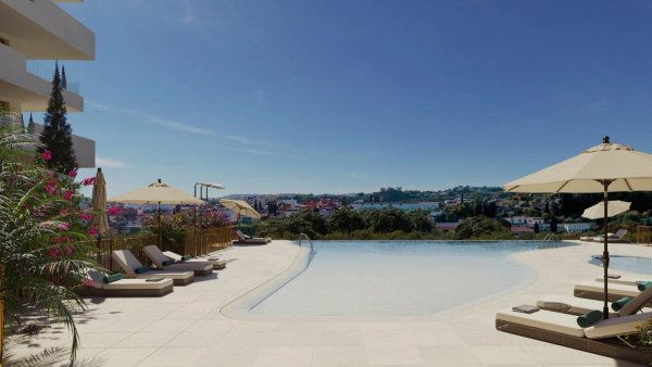 Zwembad met ligstoelen en parasols met uitzicht op Fuengirola, onderdeel van een modern penthousecomplex.