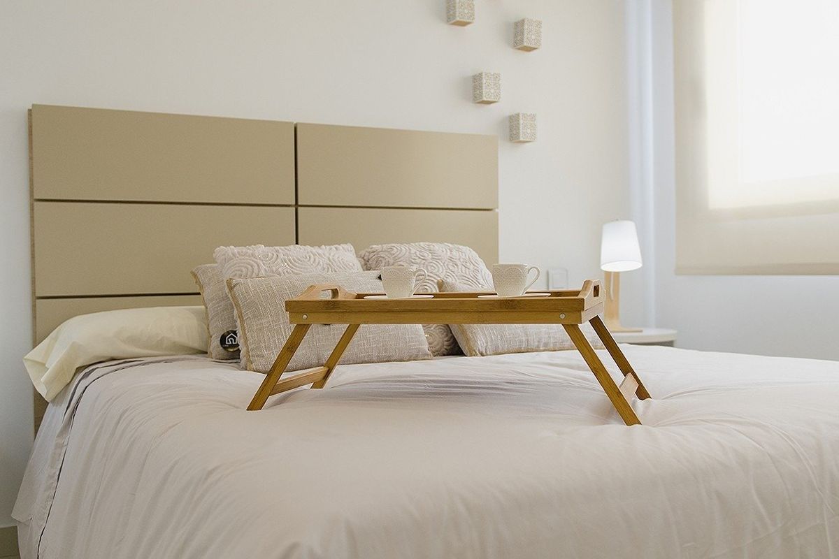 Gezellige slaapkamer in een villa met een houten dienblad op het bed, gelegen in Orihuela Costa, Spanje.