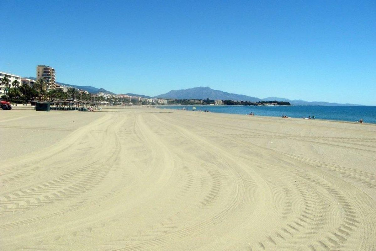 Zandstrand van Estepona met een heldere lucht en verre bergen, die de kustlijn van Costa del Sol toont.
