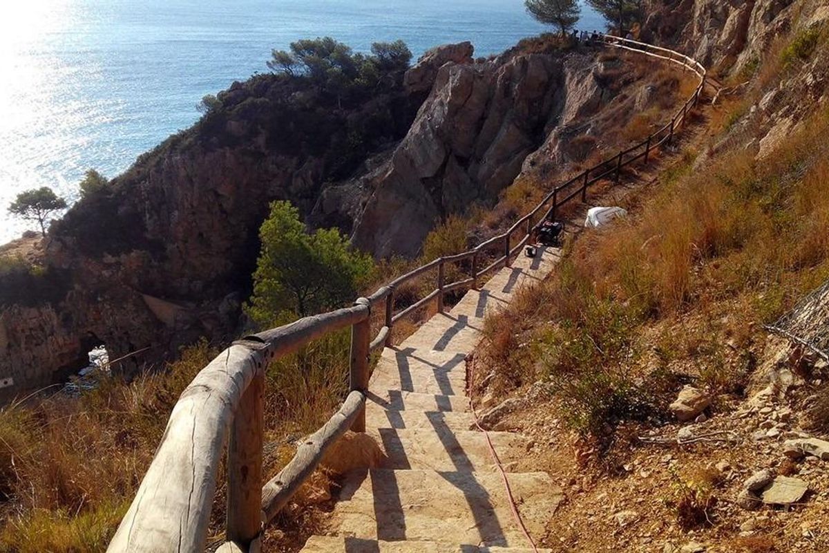 Kronkelpad dat naar de zee leidt, en de prachtige kliffen en kustlijn in Benitachell, Costa Blanca Noord, benadrukt.