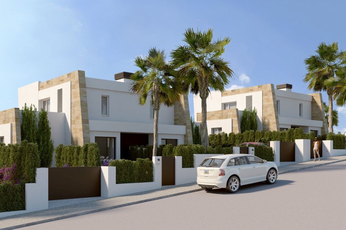 Vooraanzicht van townhouses met weelderig groen en palmbomen in Algorfa, Costa Blanca Zuid, Spanje.