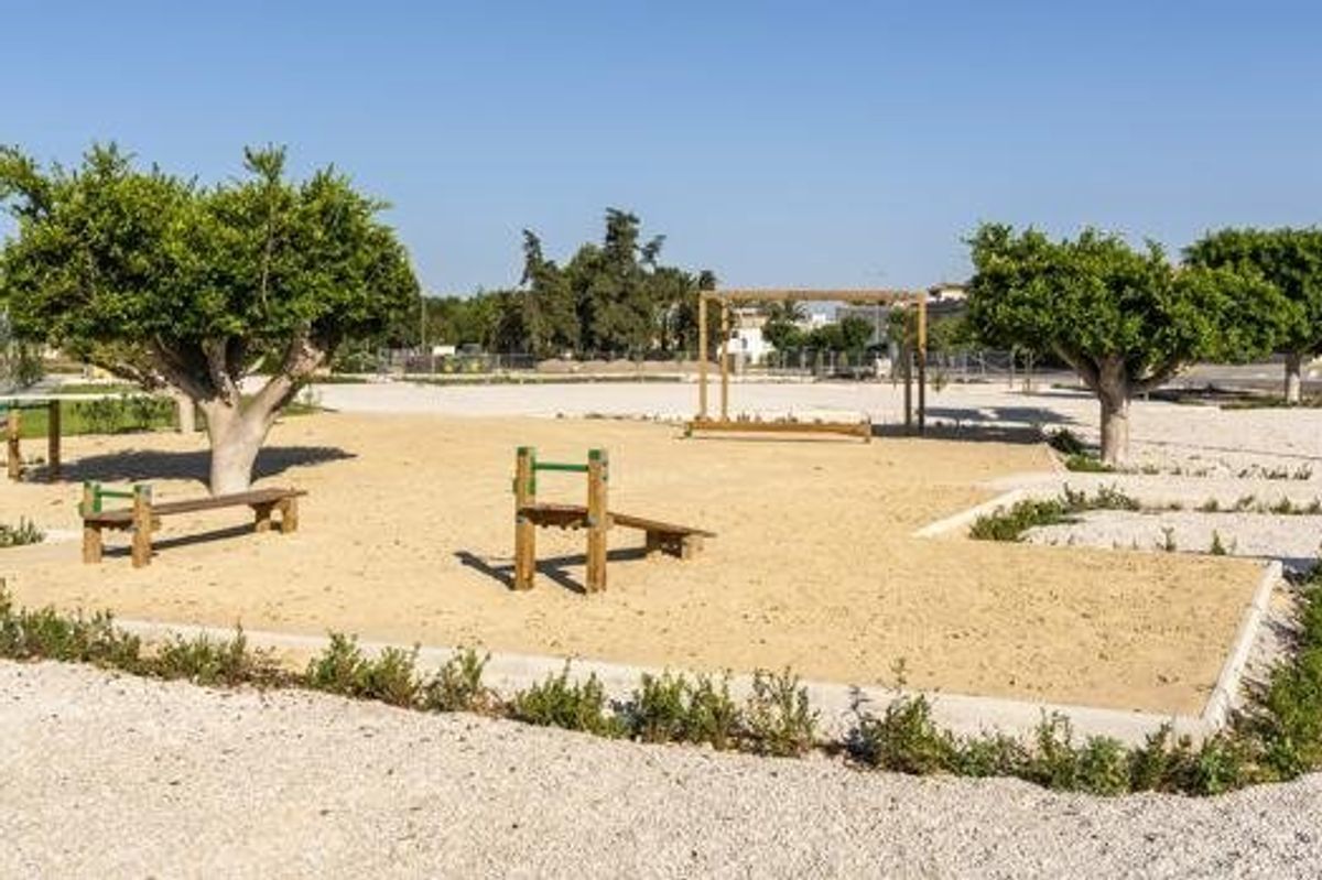 Speeltuin in Daya Nueva, Costa Blanca Zuid, Spanje, met bomen en zanderige grond voor kinderen.