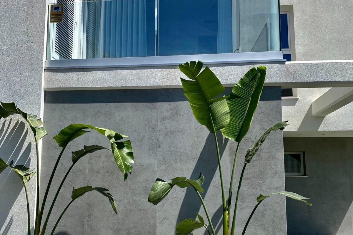 Stijlvol geveldetail van de villa in Finestrat, met glazen balkon en groenaanplanting.