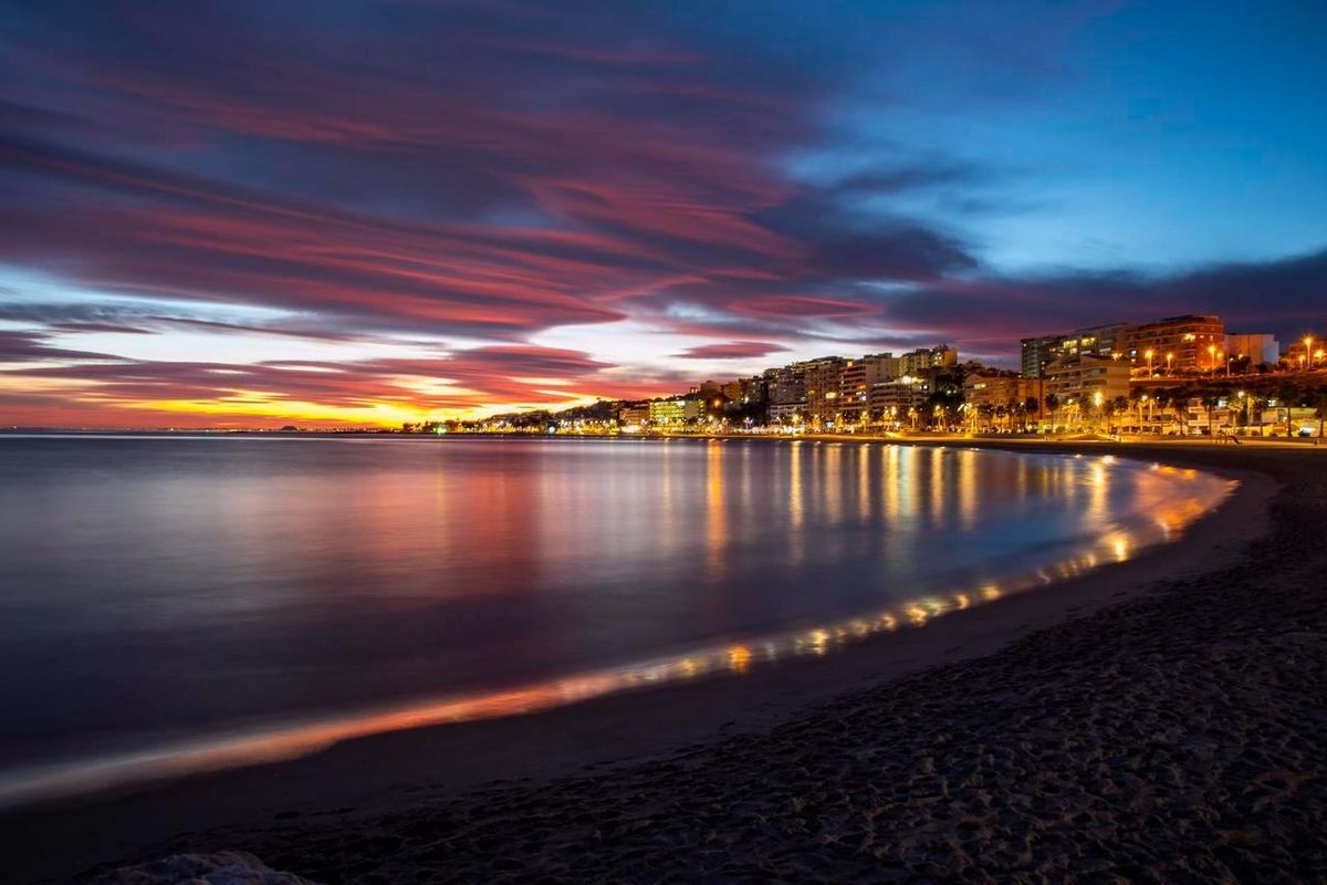 Uitzicht op het strand van Villajoyosa 's nachts, verlicht door stadslichten met een serene kustsfeer.