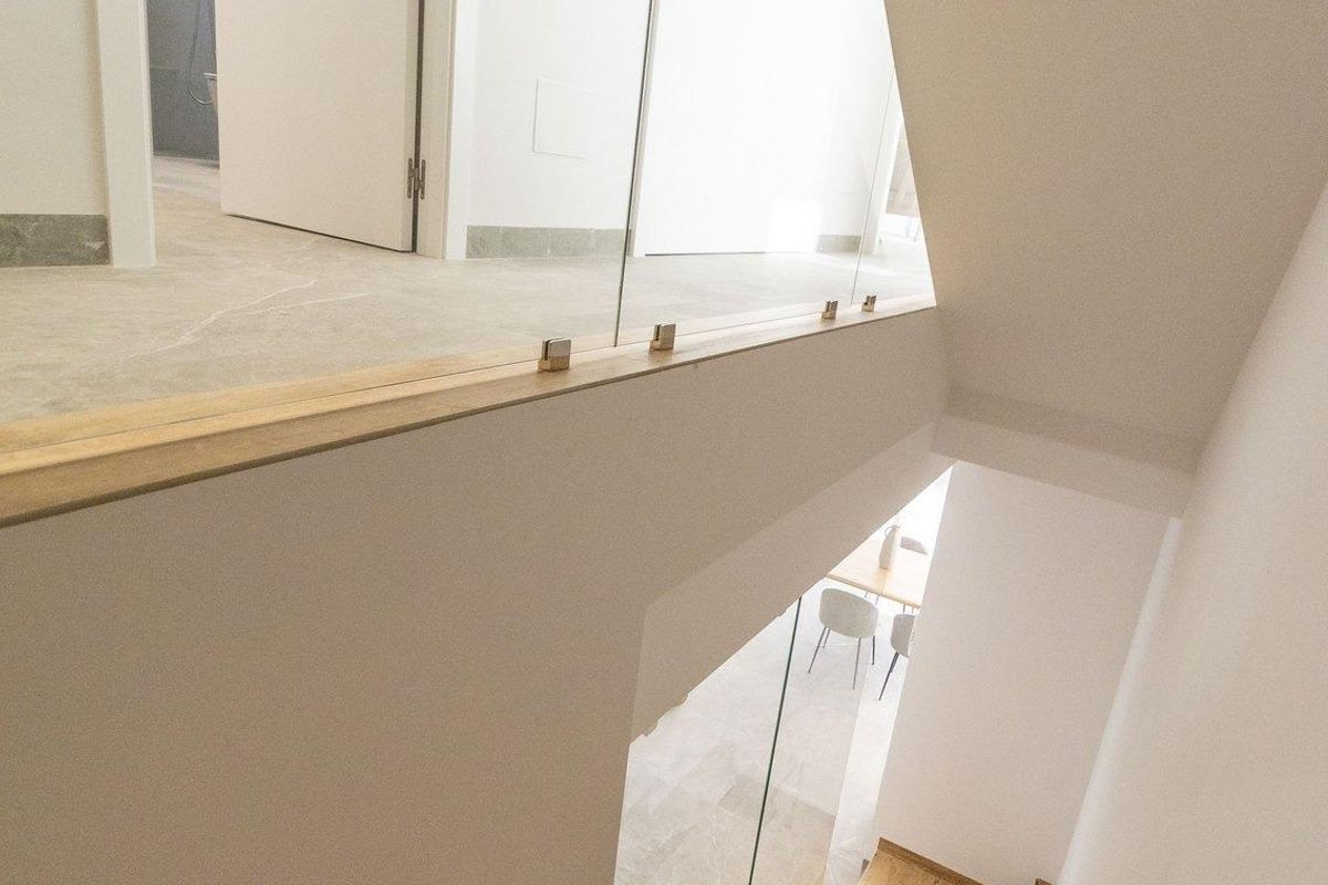 Uitzicht op de trap in een moderne villa met houten treden en glazen leuningen in Pilar de La Horadada.