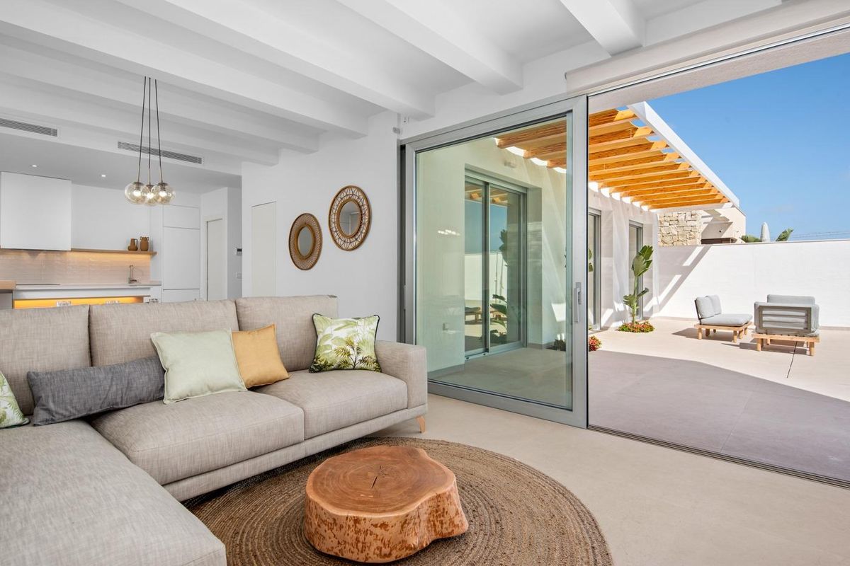 Moderne woonkamer in een 3-slaapkamer villa, Benijofar, met een gezellige bank en grote ramen met toegang tot buiten.