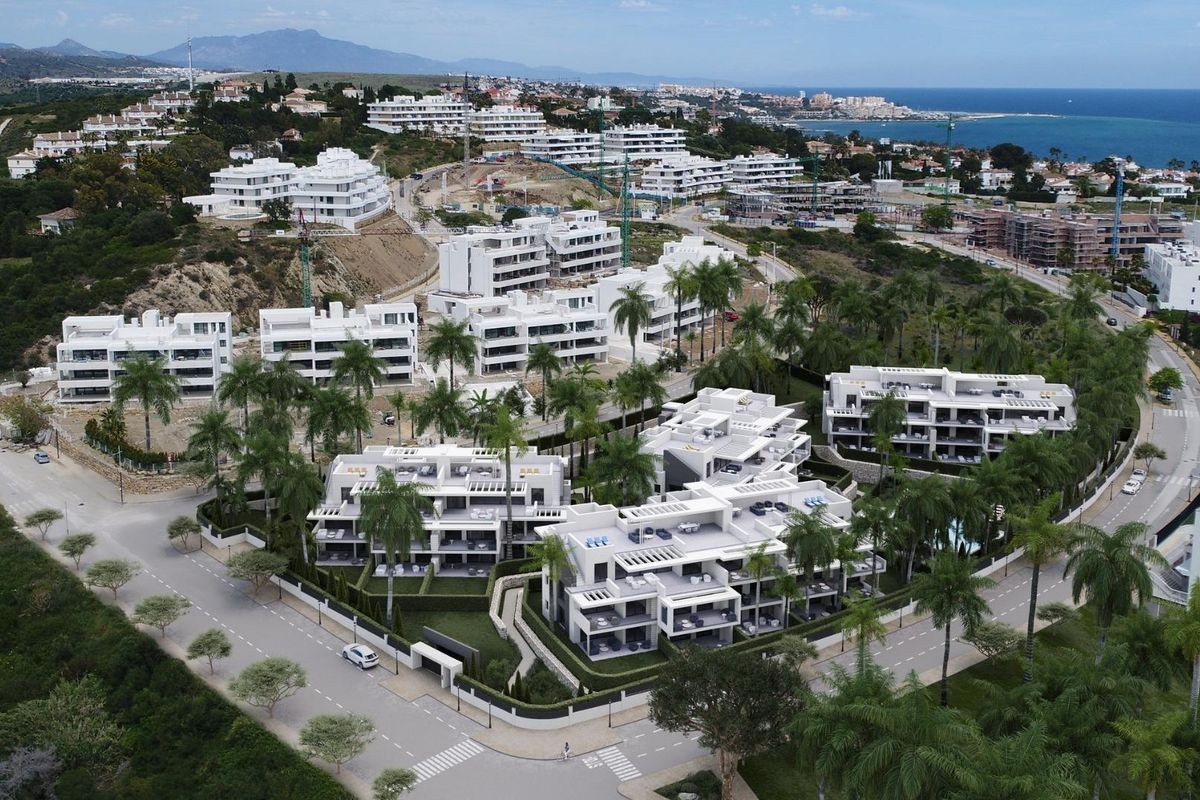 Luchtfoto van een 3-slaapkamer appartementencomplex in Estepona, Costa del Sol, omgeven door heuvels en zee.