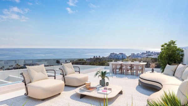 Zonnig terras met ligstoelen en eethoek, met uitzicht op zee in Estepona's penthouse.