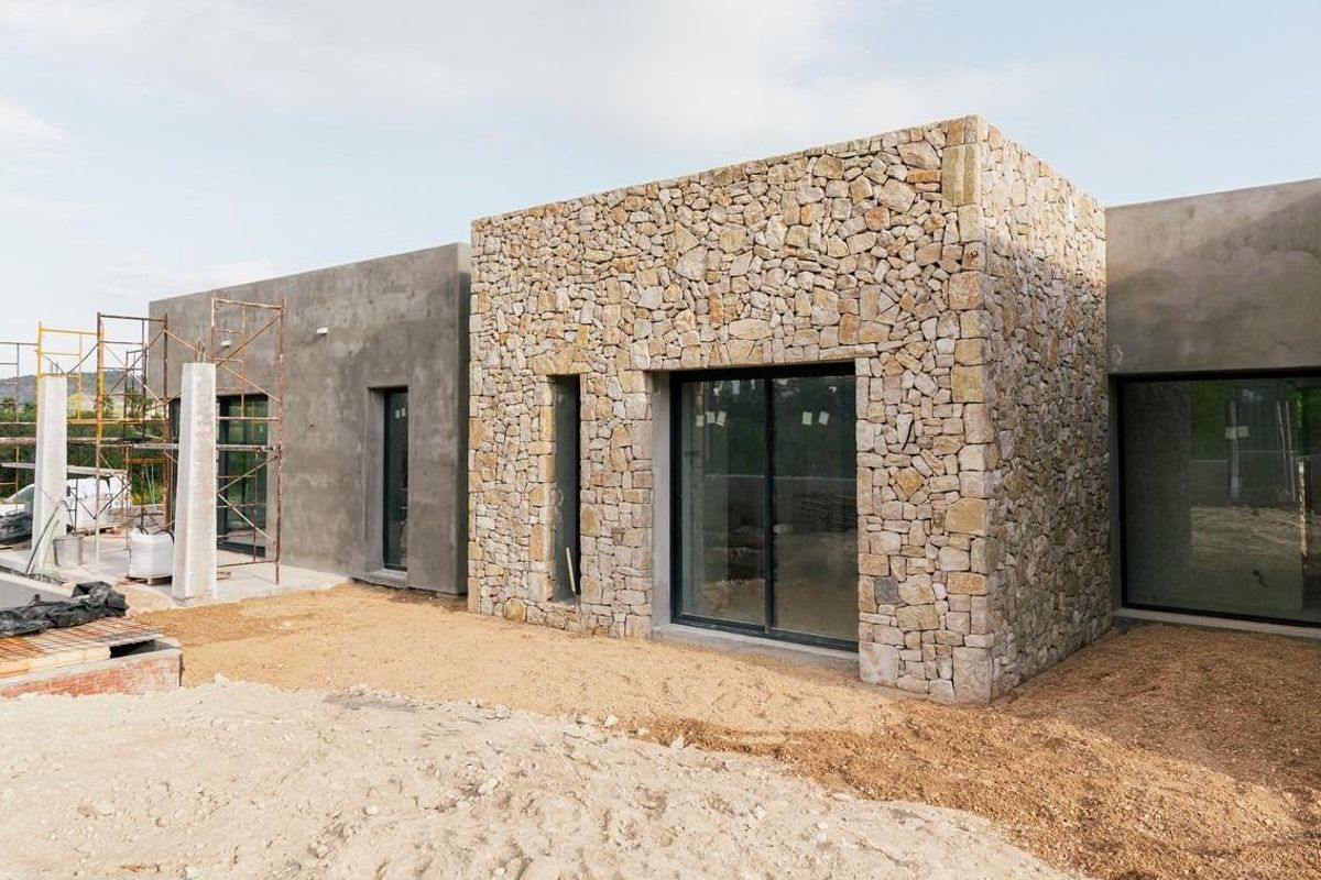 Buitenkant van een villa in aanbouw in Jávea, Costa Blanca Noord, met stenen en modern ontwerp.