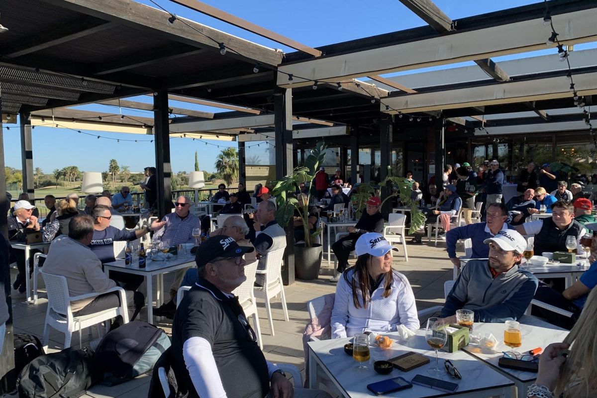 Levendige sfeer op het terrasrestaurant in het appartementencomplex, vol gasten die genieten van drankjes.