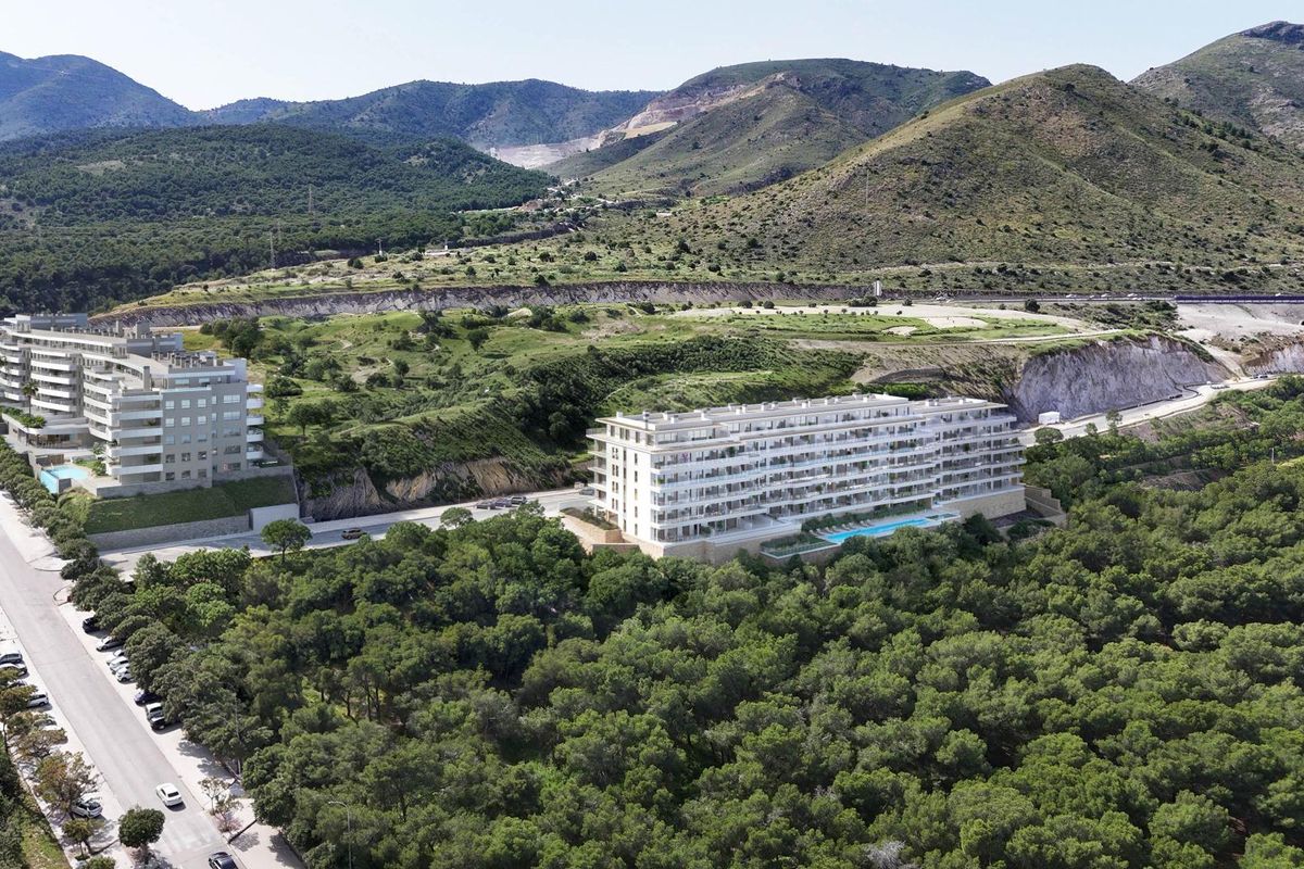 Luchtfoto van twee moderne appartementsgebouwen in Torremolinos, omgeven door groen en bergen.