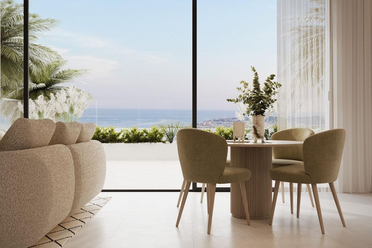 Eethoek in het penthouse met een ronde tafel en serene uitzichten op de zee en tuinen in Mijas.