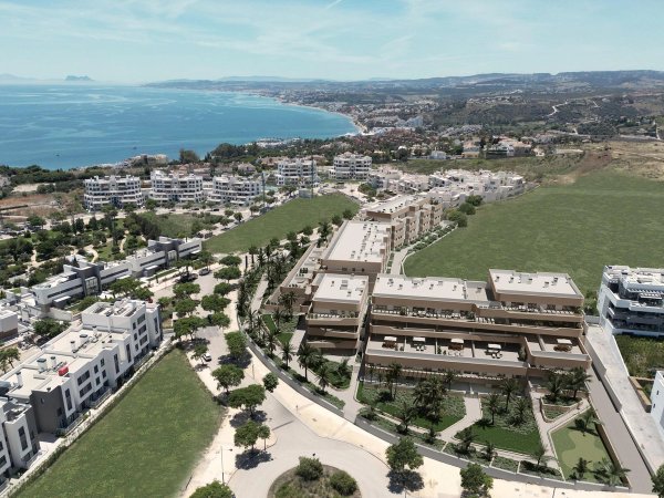 Luchtfoto van een modern 2-slaapkamerappartement nabij Estepona, Costa del Sol, met groene ruimte en kustlijn.
