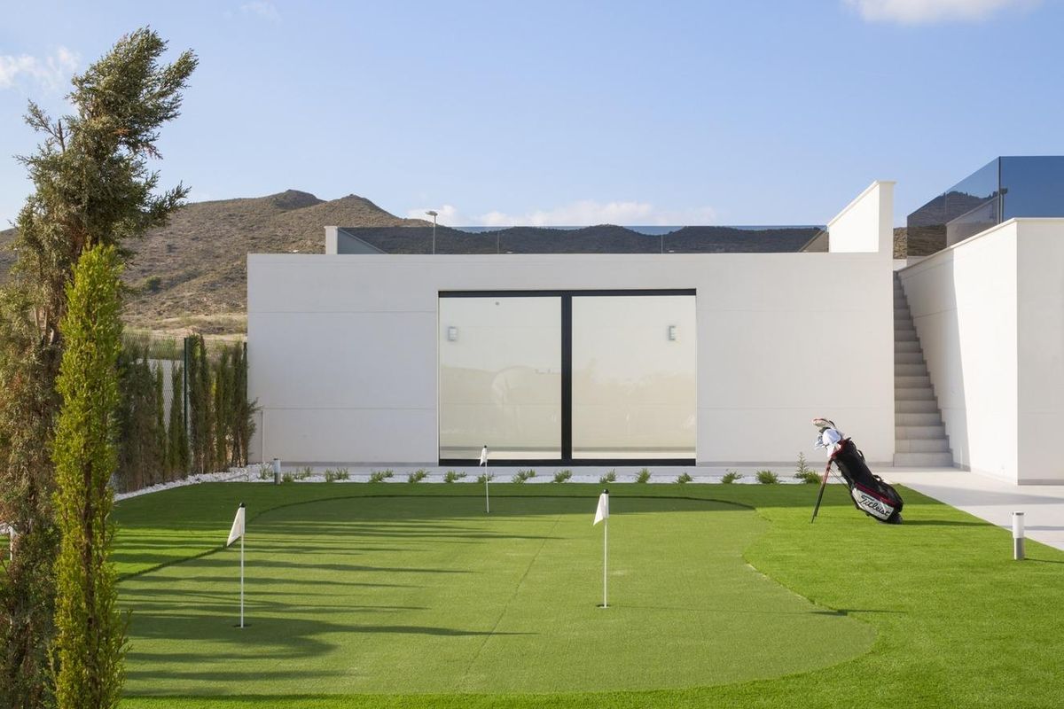 Spacious green garden with a putting green at a luxury villa in Baños y Mendigo, ideal for golf enthusiasts.