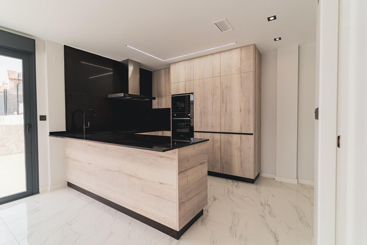 Moderne keuken met houten kasten en strakke apparaten in een villa in Orihuela Costa, Spanje.