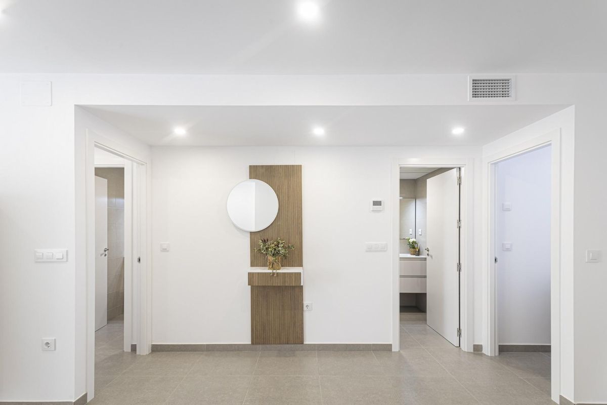 Gang met een spiegel en decoratieve plant in een modern appartement in La Manga del Mar Menor.