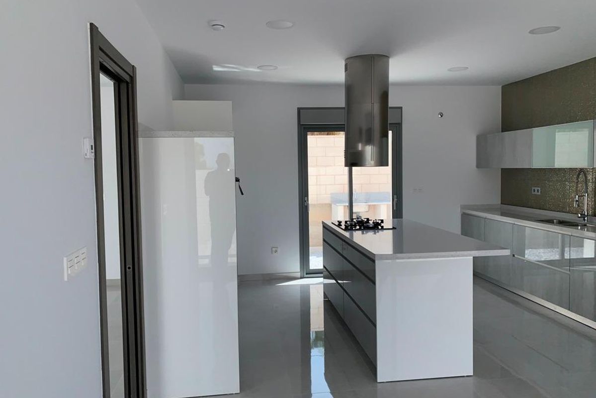 Heldere keukengedeelte met een moderne kookeiland en roestvrijstalen apparaten in een villa in Pinoso.