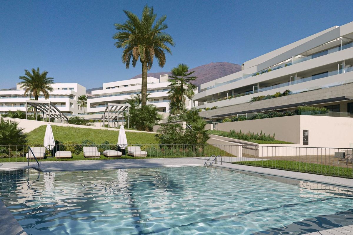Aantrekkelijk zwembadgebied in het moderne 3-slaapkamer appartementcomplex in Estepona, met ligbedden en palmbomen.
