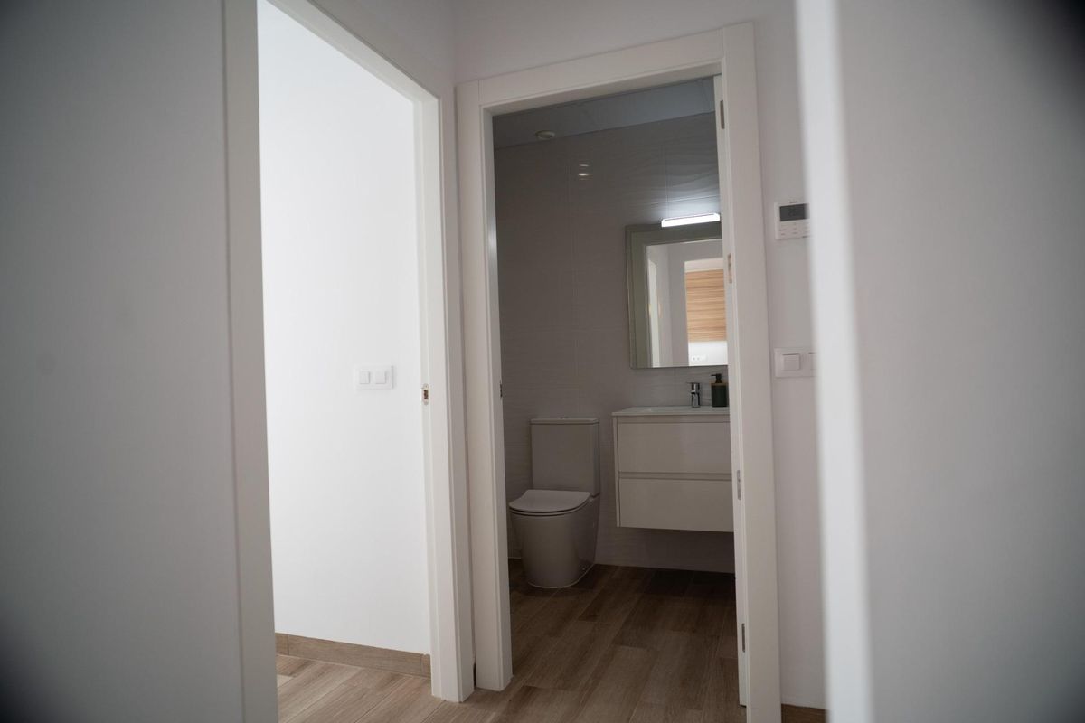View through doorway into a modern bathroom featuring toilet, sink, and mirror in a San Javier townhouse.