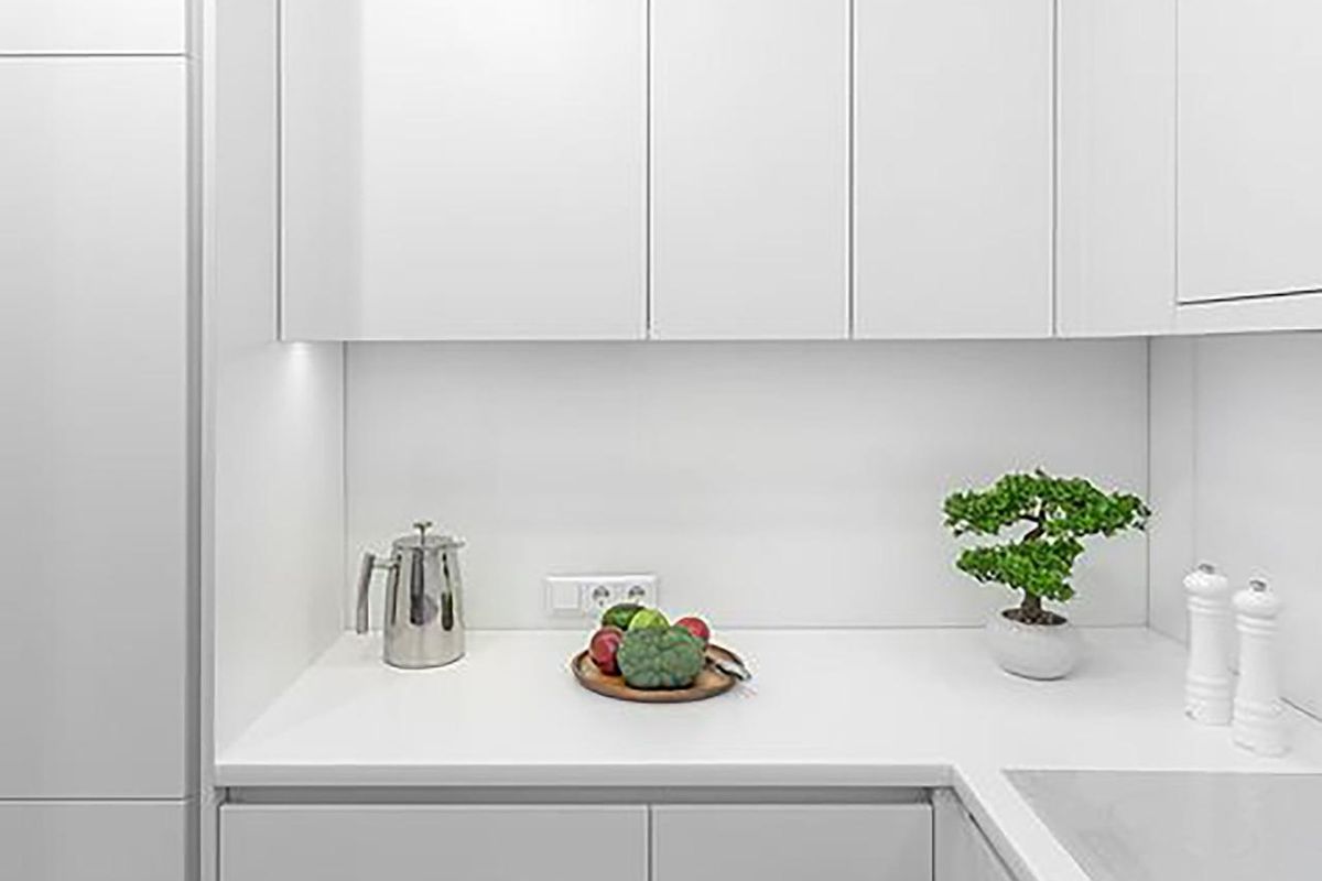 Detail of modern kitchen in apartment in Relleu, with white cabinets, counter, and view of cooking preparation area.