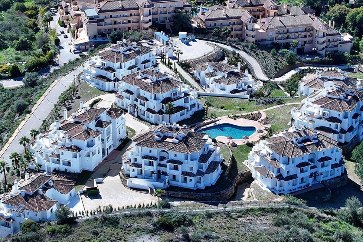Luchtfoto van een wooncomplex met meerdere gebouwen en een gedeeld zwembad in Marbella, Spanje.