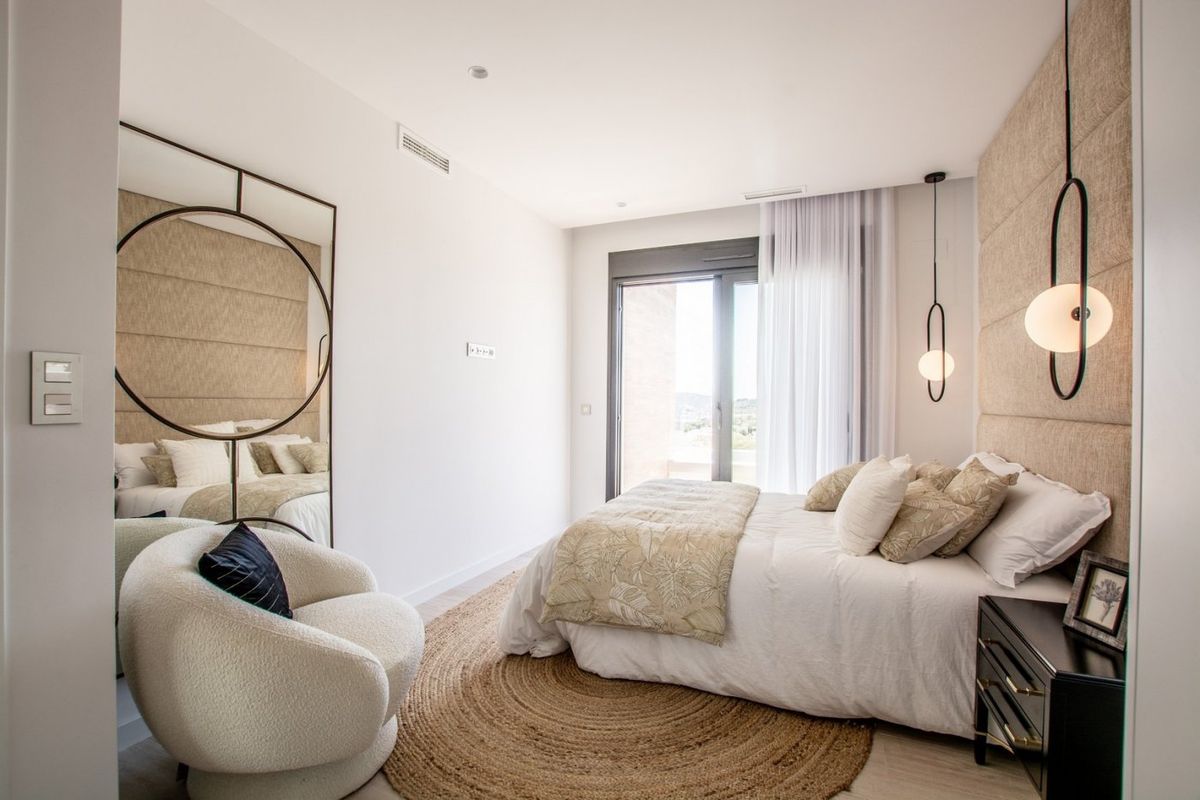 Bedroom of a 4-bed villa in Finestrat, featuring a double bed, round mirror, and elegant bedside table with lamp.
