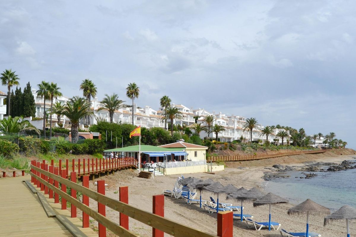Promenade aan het strand met ligbedden en restaurants nabij de prachtige kust van Mijas, Spanje.