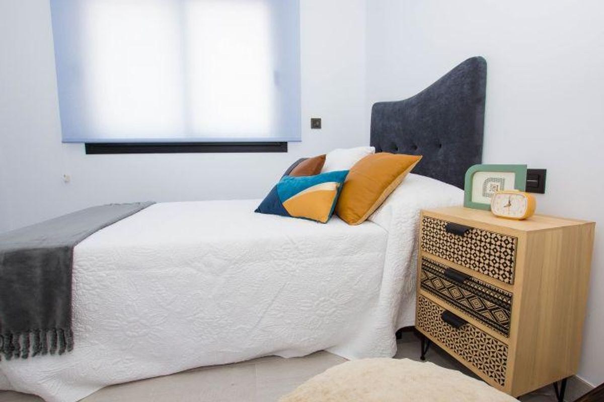 Gezellige slaapkamer met wit beddengoed, grijze hoofdeinde en houten nachtkastje in Spaanse villa