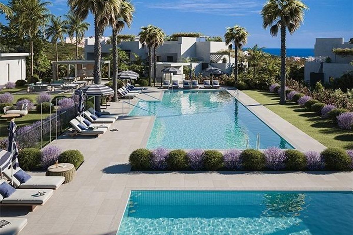 Resortachtige zwembad omringd door palmbomen en ligstoelen, ideaal voor ontspanning in Costa del Sol, Casares.