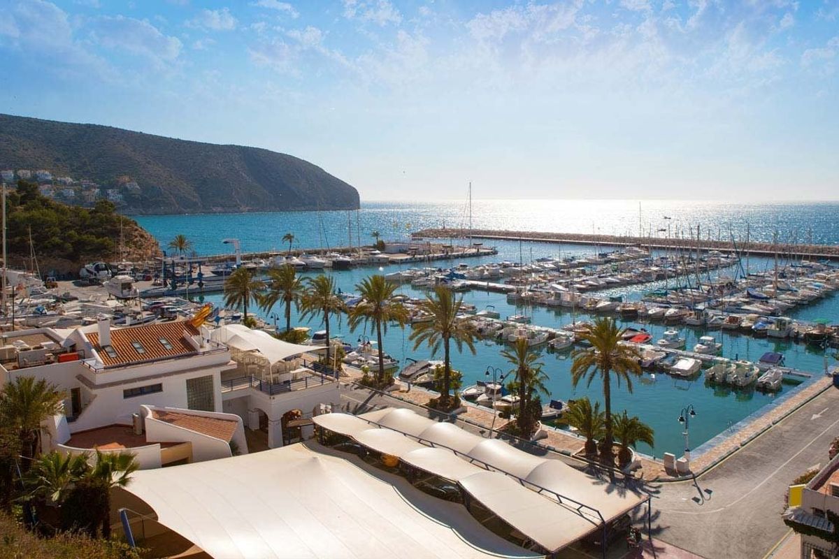 Levendig uitzicht op de jachthaven in Moraira Teulada, Costa Blanca, met luxe boten en eetgelegenheden aan zee.