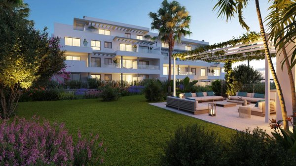 Moderne witte 3-slaapkamer appartementscomplex met aangelegde tuin in Mijas, met buitenruimte en palmbomen bij avondschemering