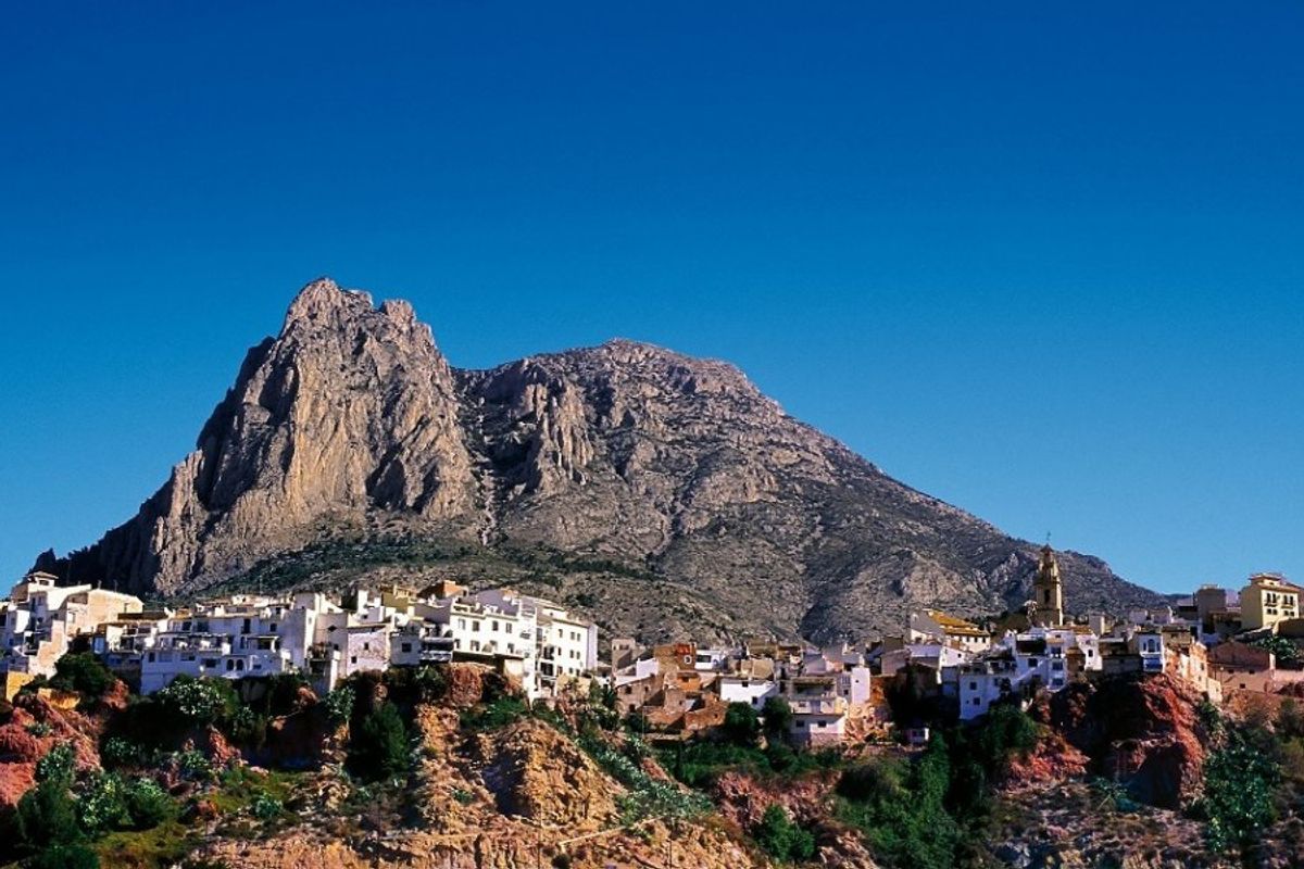 Panoramisch uitzicht op het pittoreske dorp nabij Finestrat, gelegen op een heuvel met een prominente berg op de achtergrond.